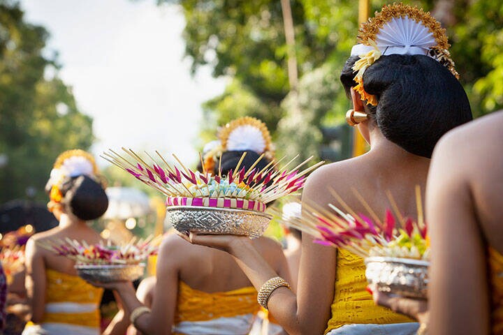 Procession of beautiful Balinese women in traditional costumes - sarong, carry offering on heads for Hindu ceremony. Arts festival, culture of Bali island and Indonesia people, Asian travel background