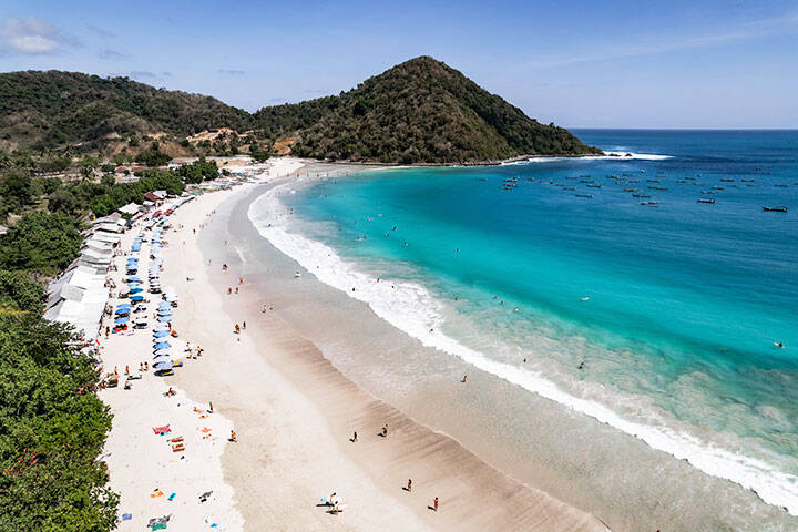 Tourists enjoying Tanjung Aan Beach in Lombok, Indonesia on sunny day 