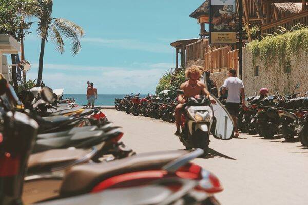 Surfer riding a motorbike and bike Parking at Berawa Beach by Surgey Chuprin