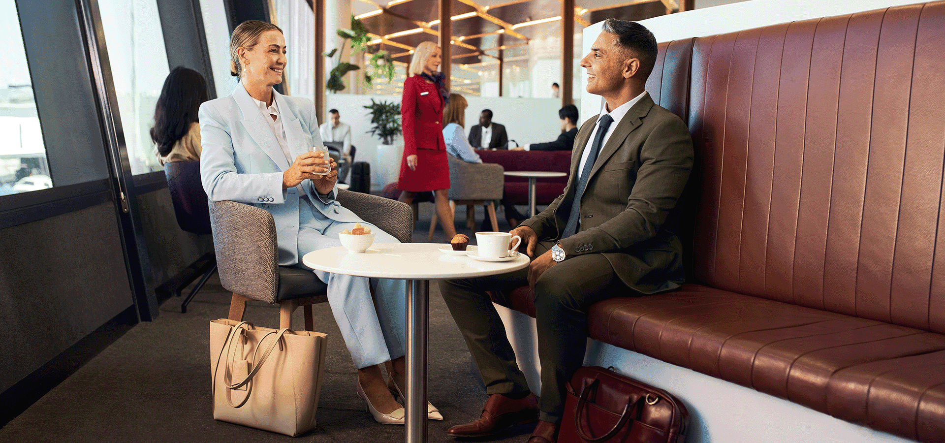 Two guests sitting in Virgin Australia lounge talking while on corporate travel trip.