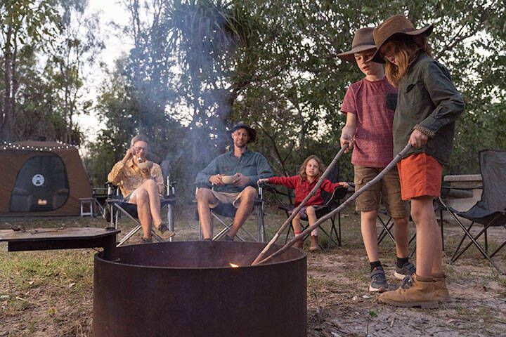 Family making dinner over a fire while camping in Kakadu